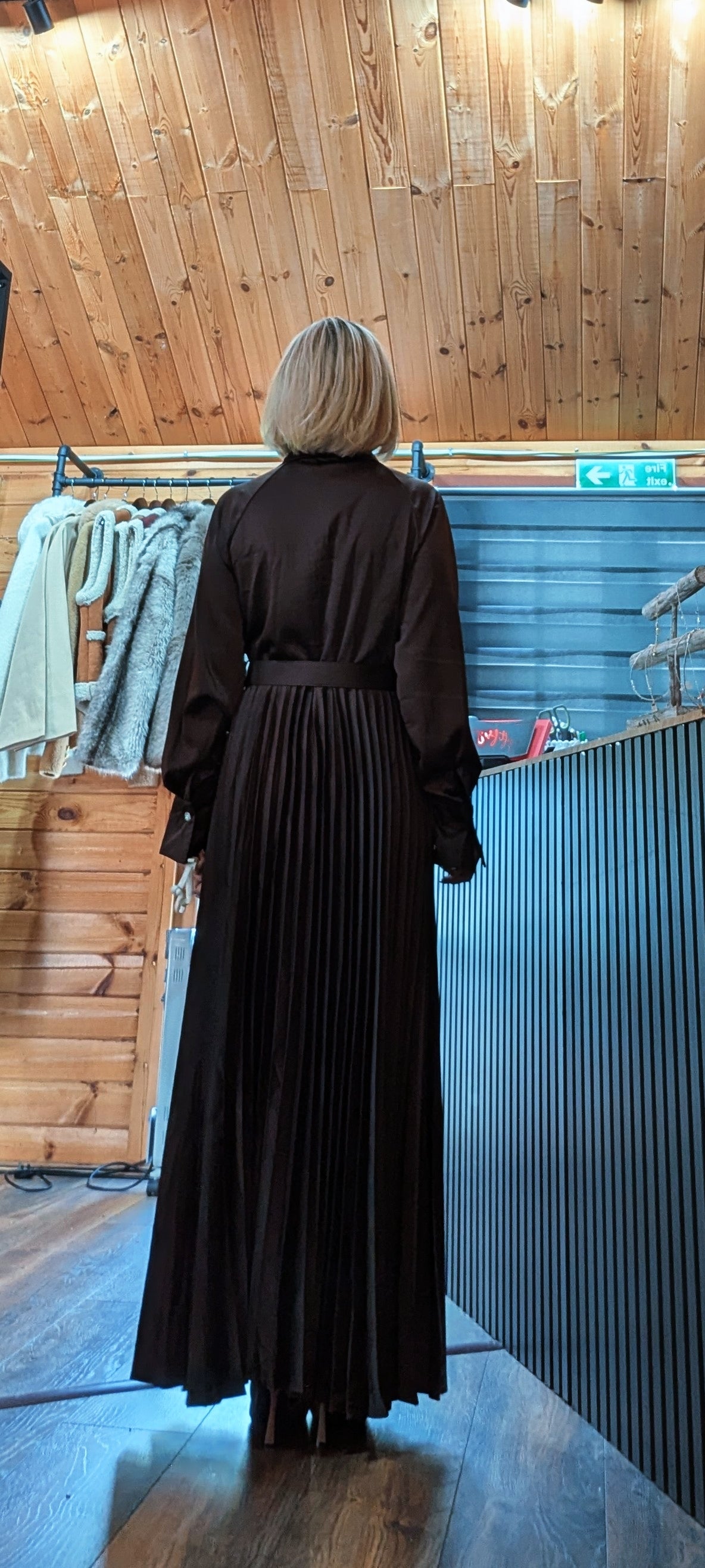 Rear view Meryl chocolate dress with long sleeves and a flowing pleated maxi skirt