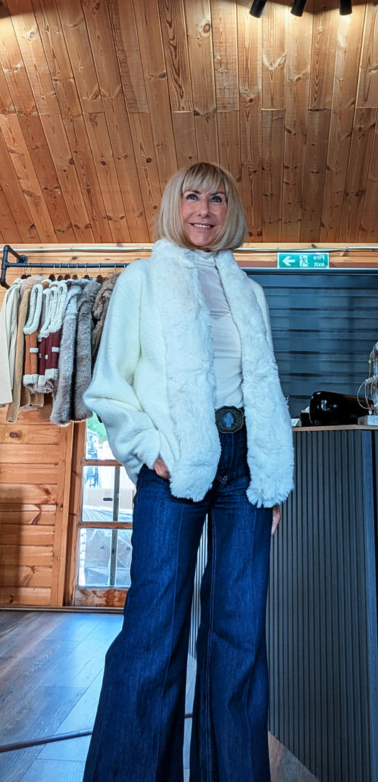 Woman wearing the Judy ivory faux fur-trimmed jacket with wide-leg jeans