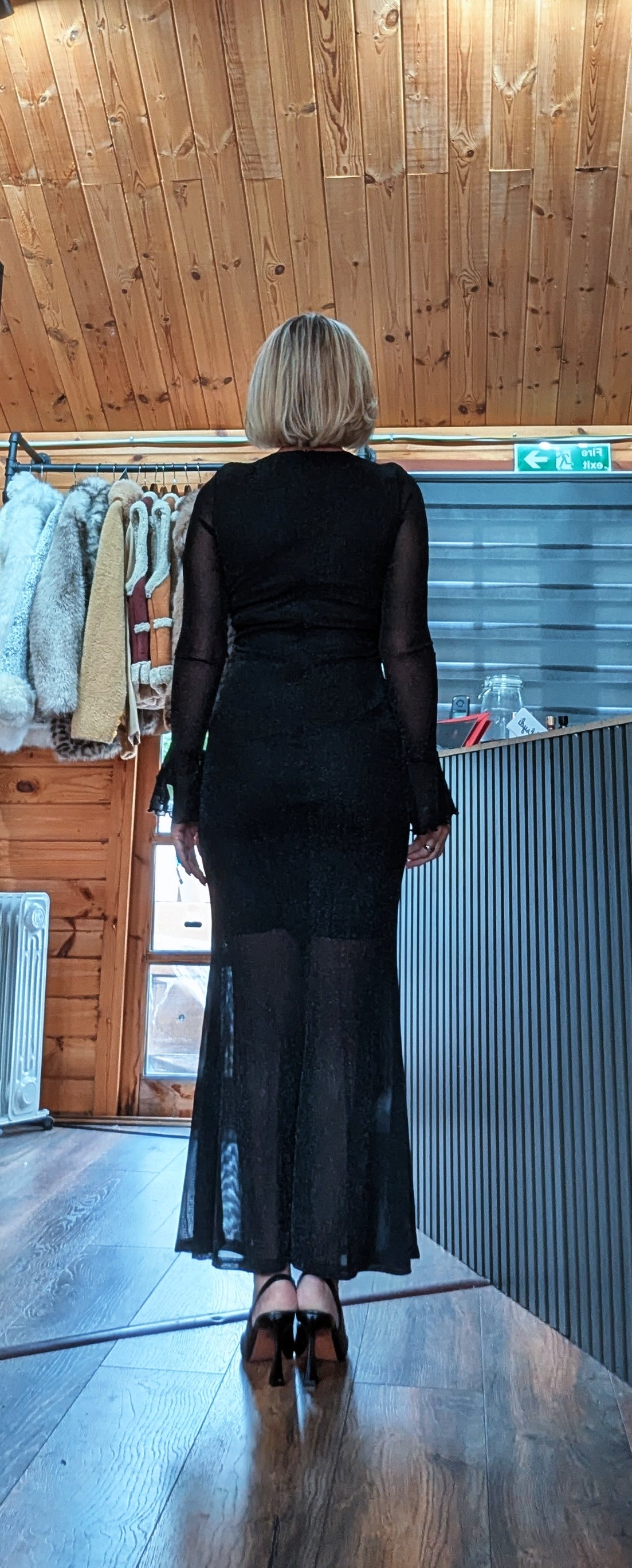 Back view of Shirley black glitter mesh dress showing the sheer sleeves and longer mesh hem