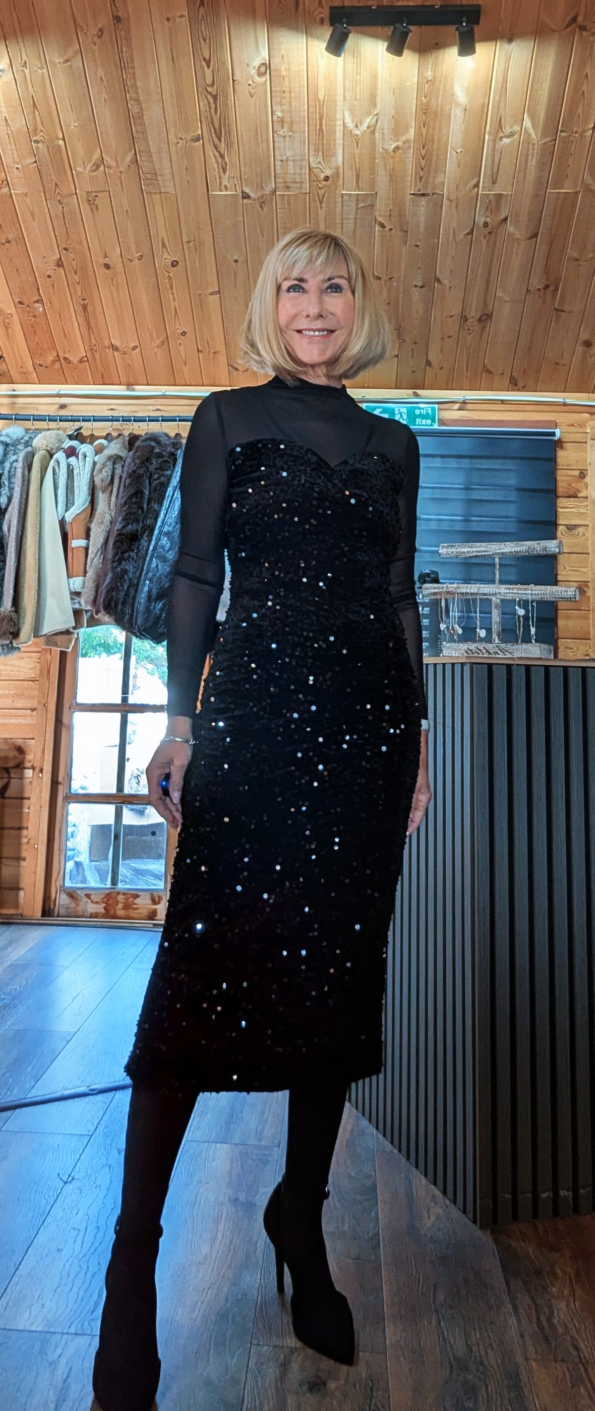 Di wearing the Audrey black sequin midi dress at an angle with one foot forward.