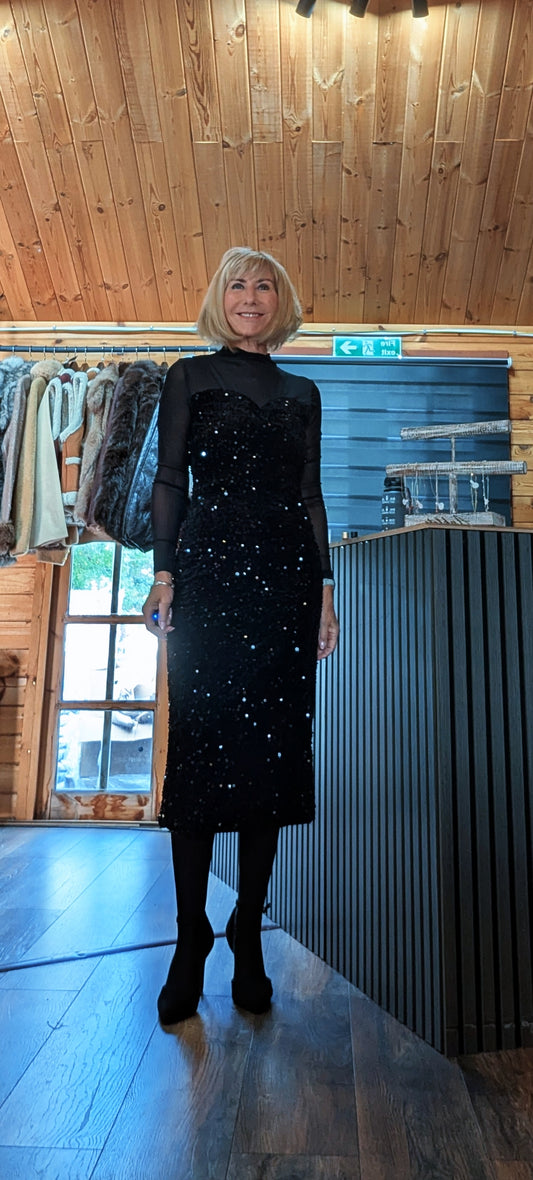Front view of the Audrey black sequin dress styled with a black shoulder bag and boots.