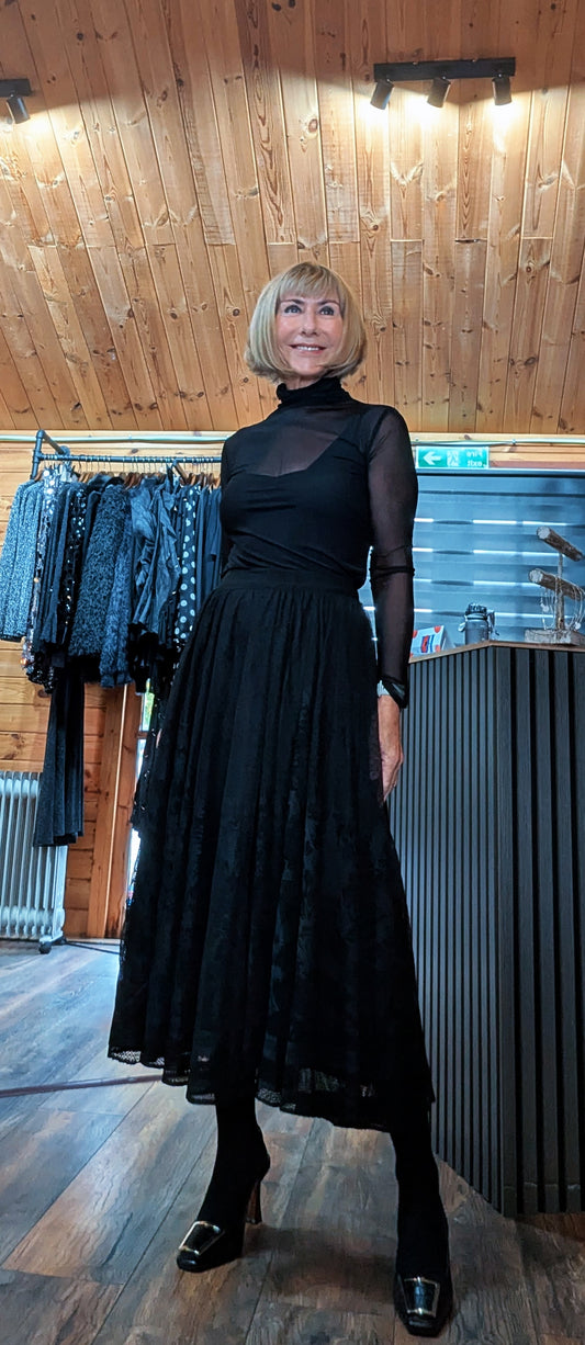 Full-length front view of the Erin black lace skirt styled with tights and buckle shoes