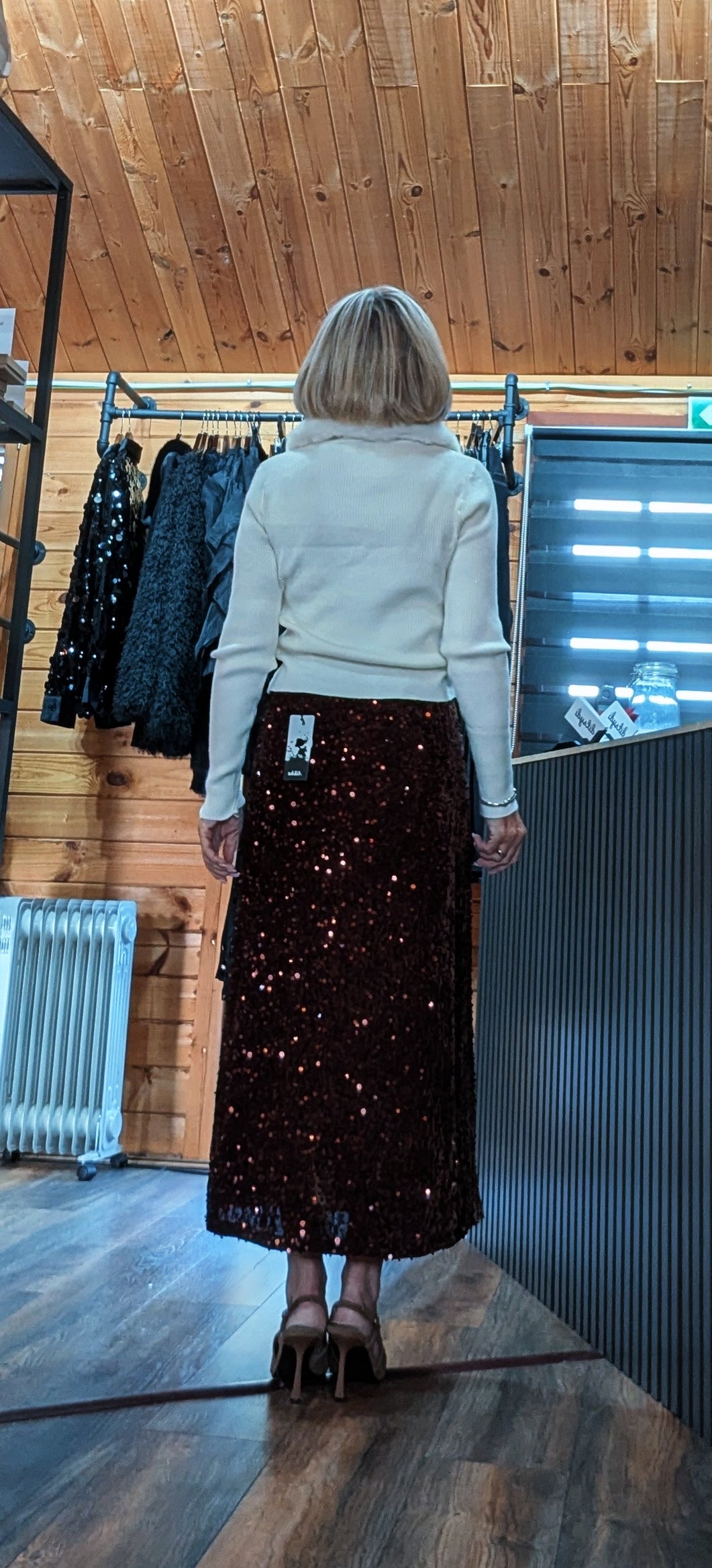 Back view of Astrid chocolate sequin skirt showing its midi length and flared hem