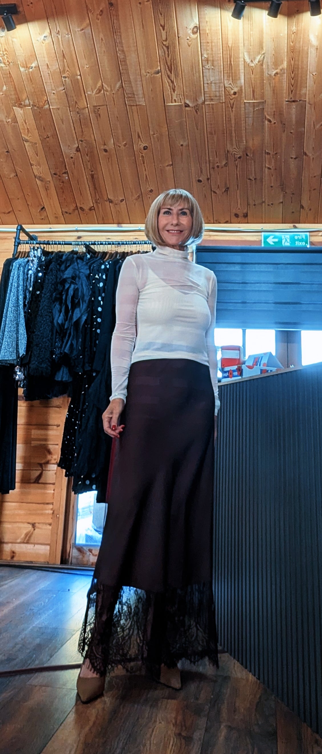 Full-length view of the Lumine chocolate skirt, showing its satin finish and floral lace hem