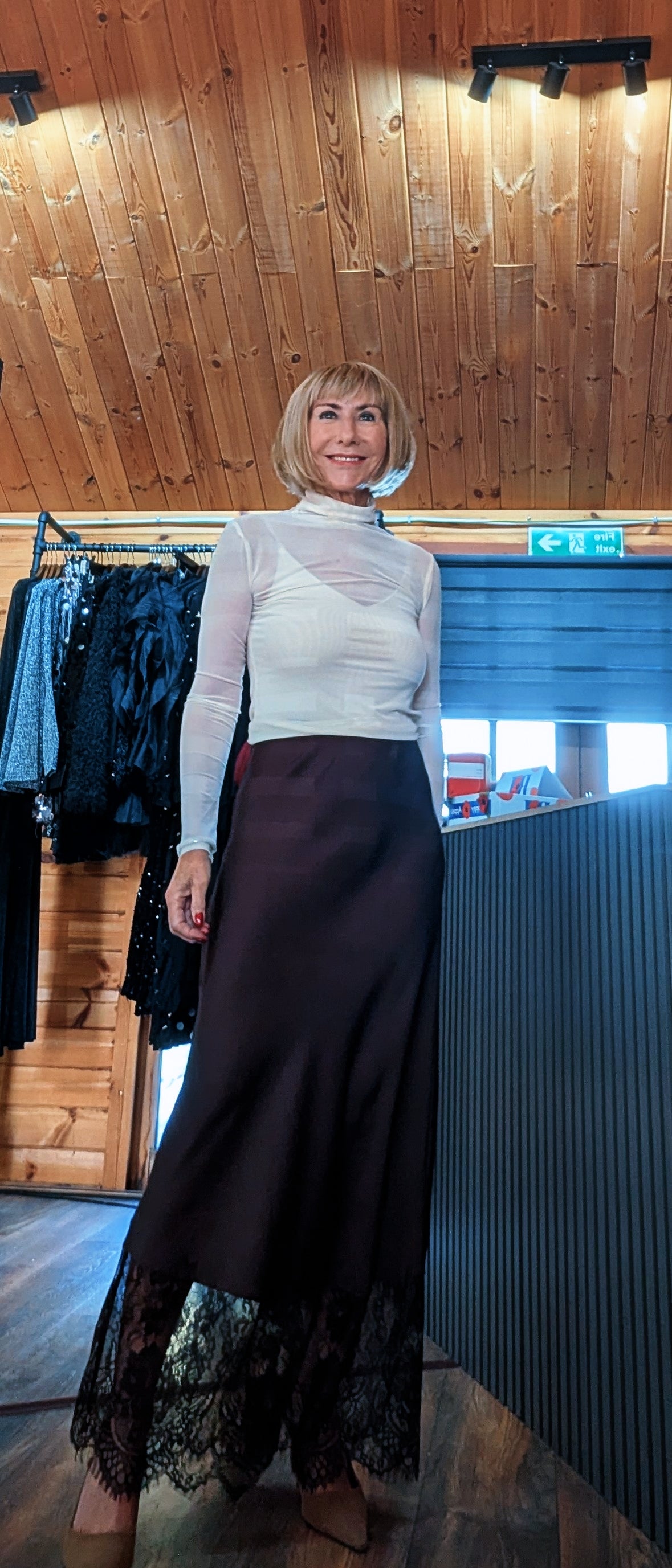 Angled view of the Lumine chocolate satin slip skirt and scalloped lace hem