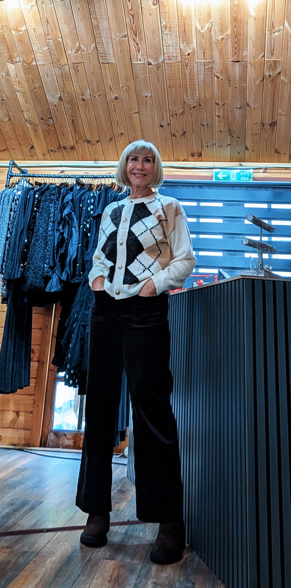 Angled view of Di wearing the Irene cardigan with black trousers