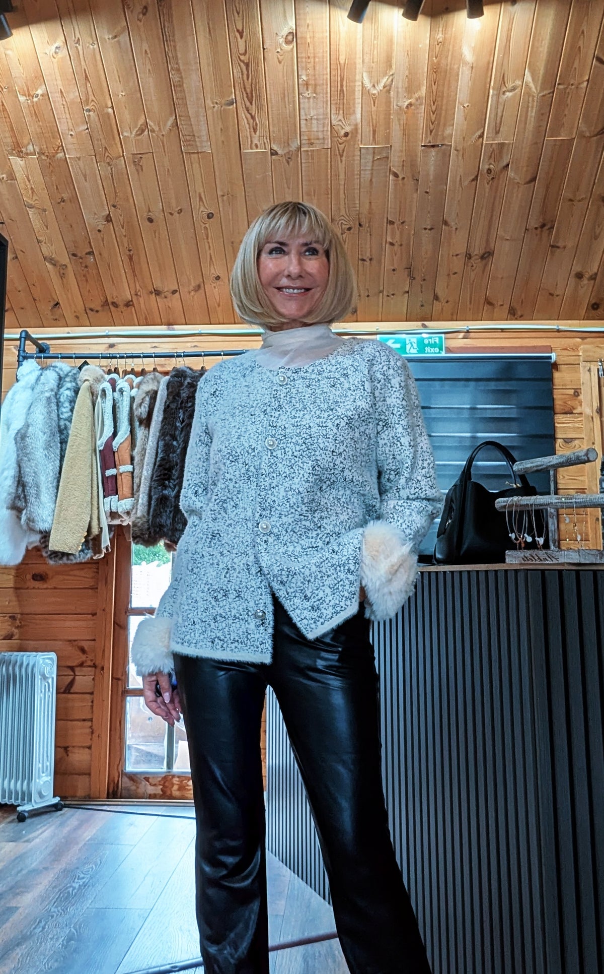 Liv white textured cardigan modelled with one hand in a trouser pocket and faux fur cuffs visible