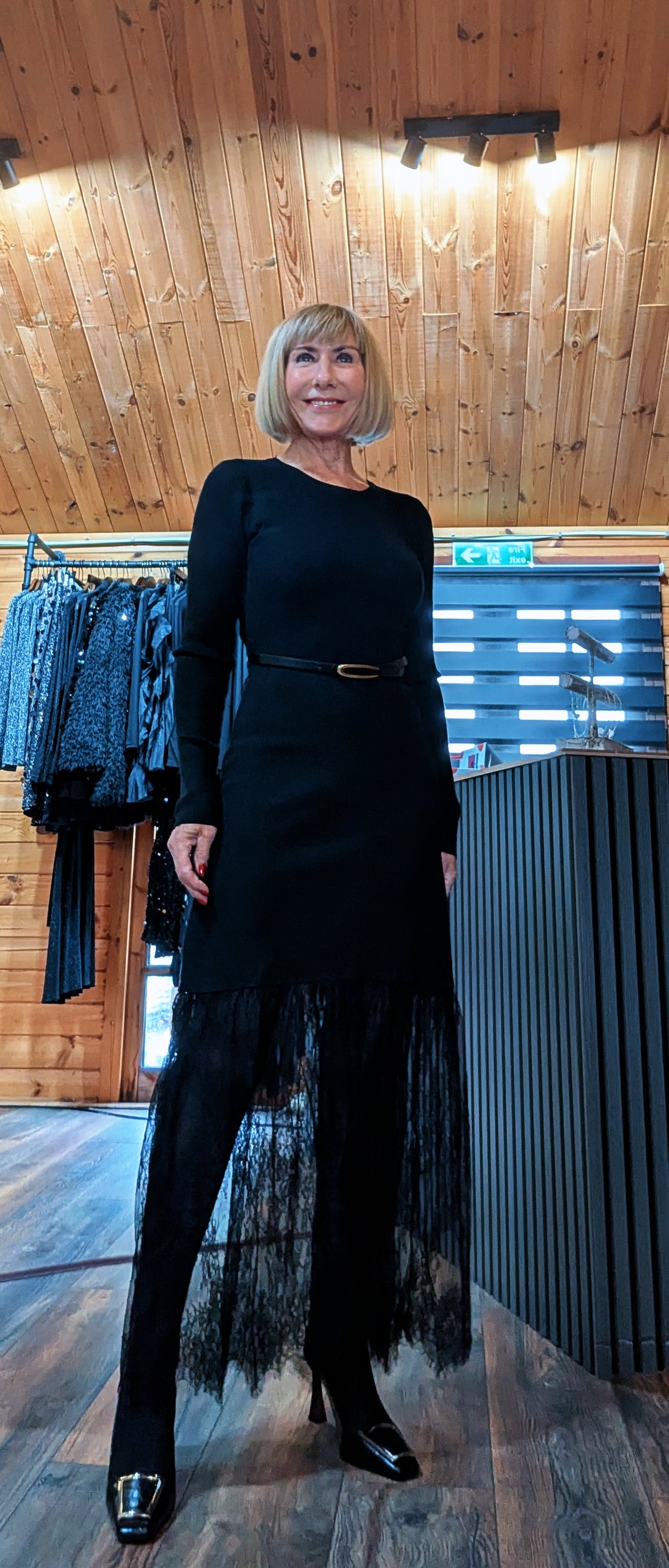 Angled front view of the Aoife dress with its slim waist belt and flowing lace detail