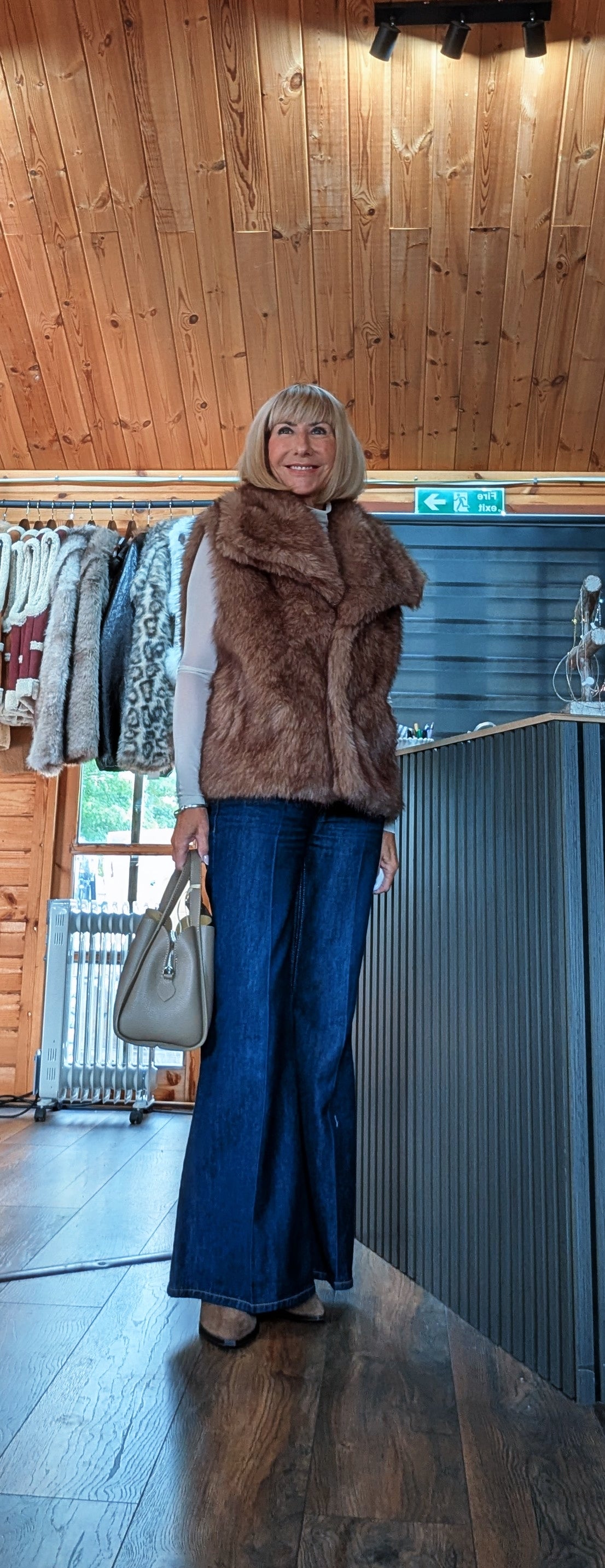 ocolate faux fur sleeveless gilet for autumn and winter styled with flared jeans and leather tote bag