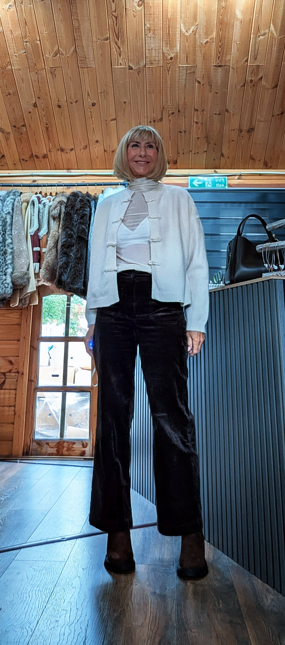 Fran cream cardigan layered over a white top with dark cropped trousers and boots