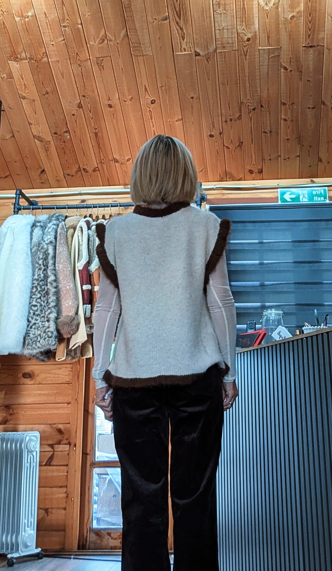 Back view of Maura beige sweater showing the plain knit back and chocolate-brown trims