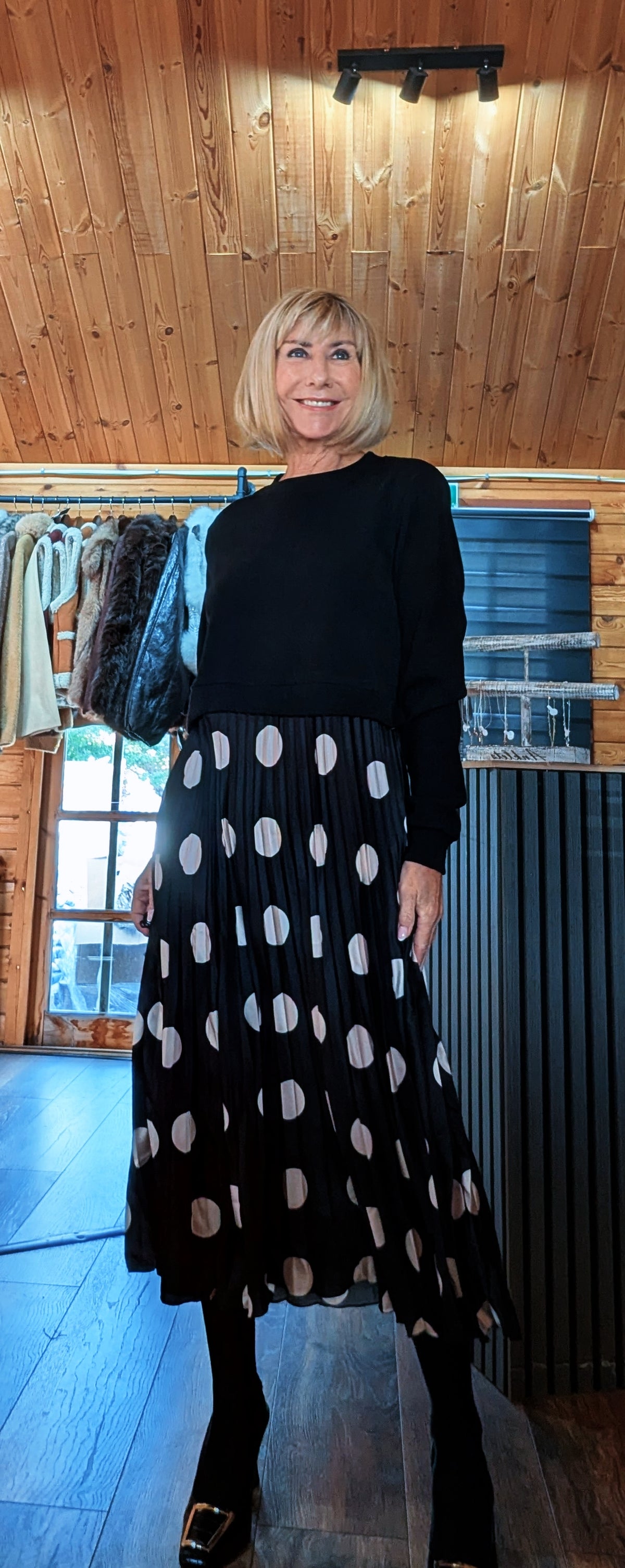 Angled front view of Hettie showing the flowing pleated skirt and oversized white polka dots.