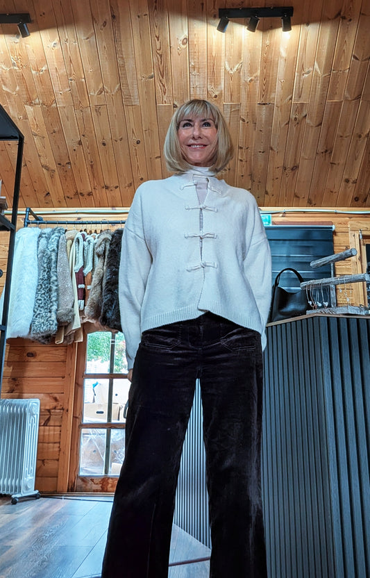 Front view of Fran cream cardigan with knot closures, styled with dark wide-leg trousers