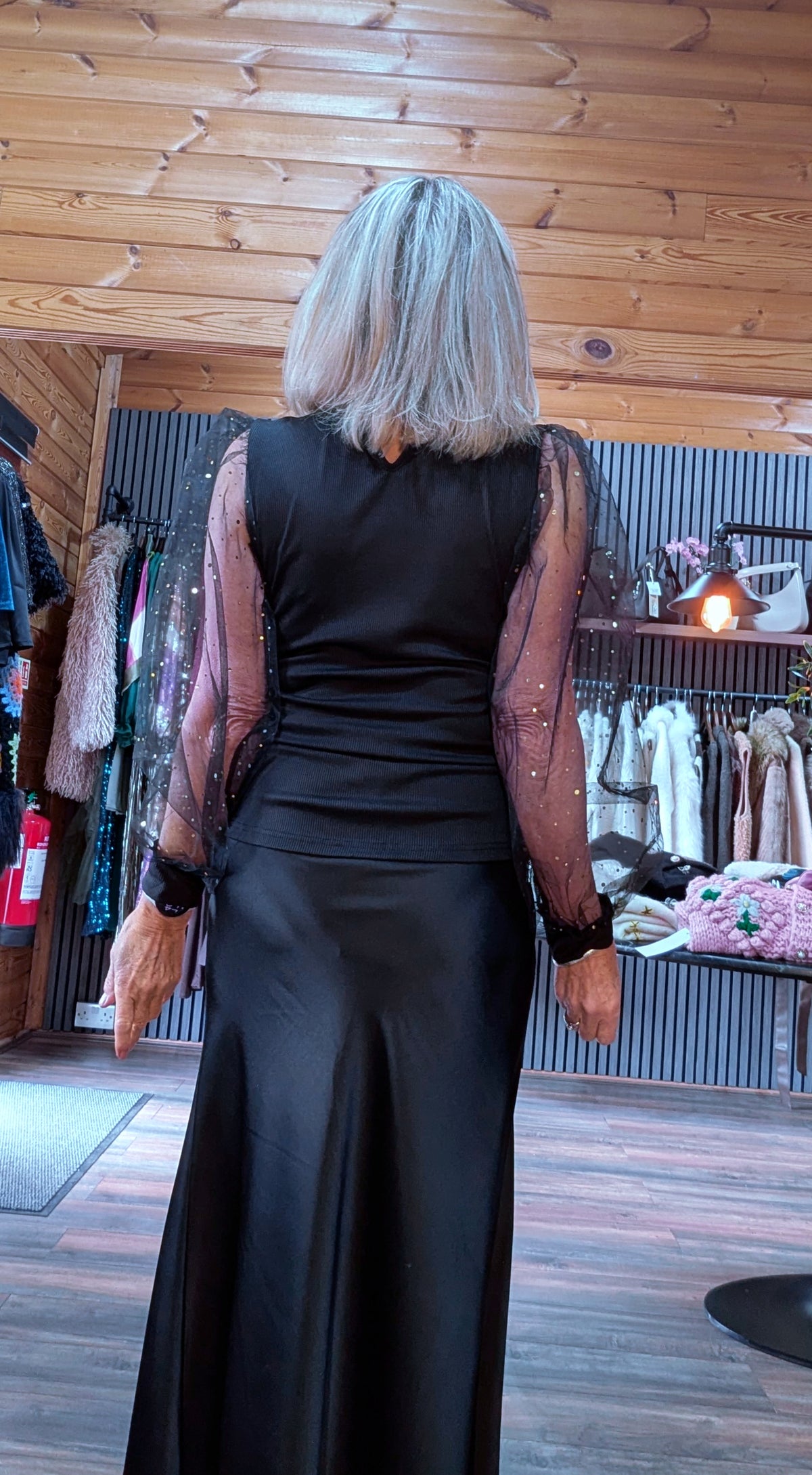 Back view of Sia black top showing the opaque back and sheer long sleeves