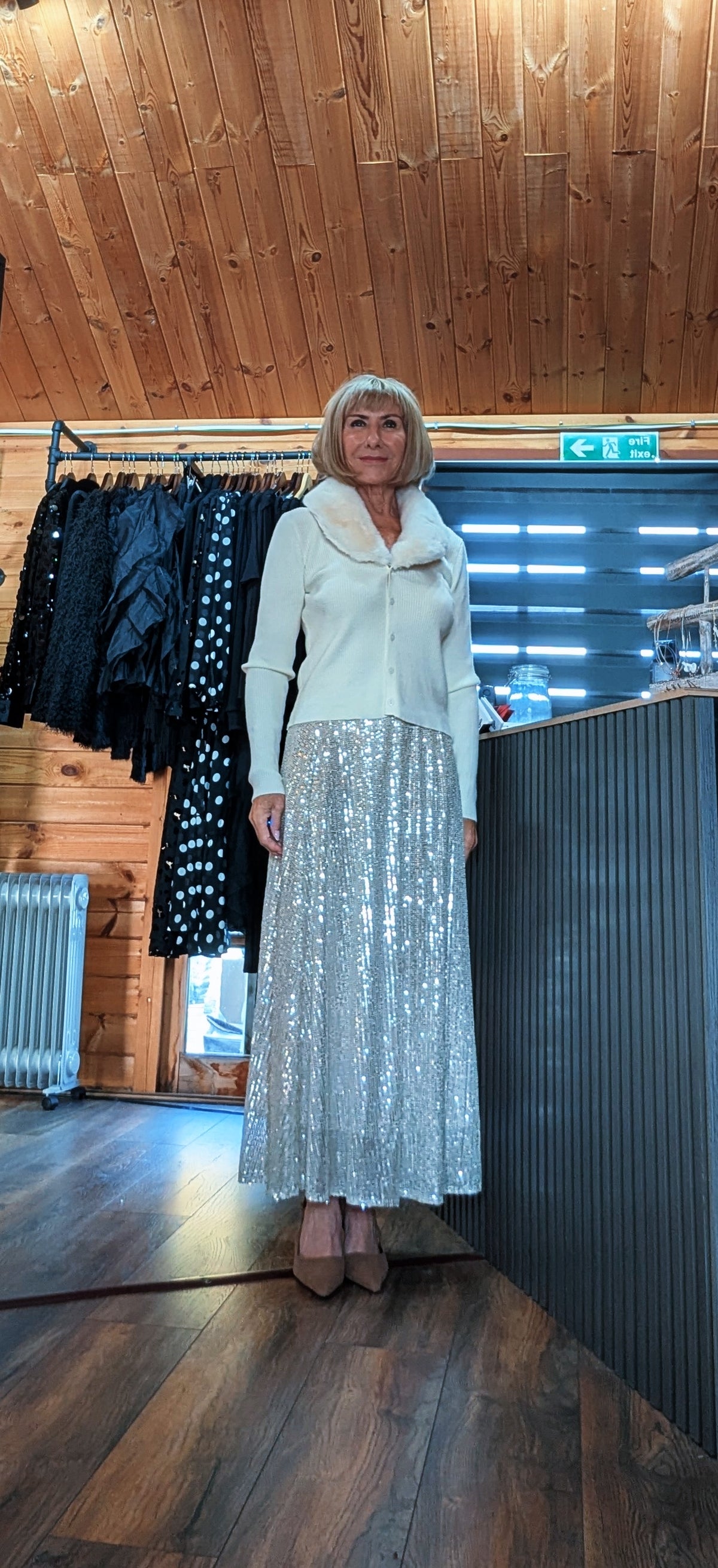 Full-length view of Cher champagne sequin skirt styled with a cream knit top and pointed heels
