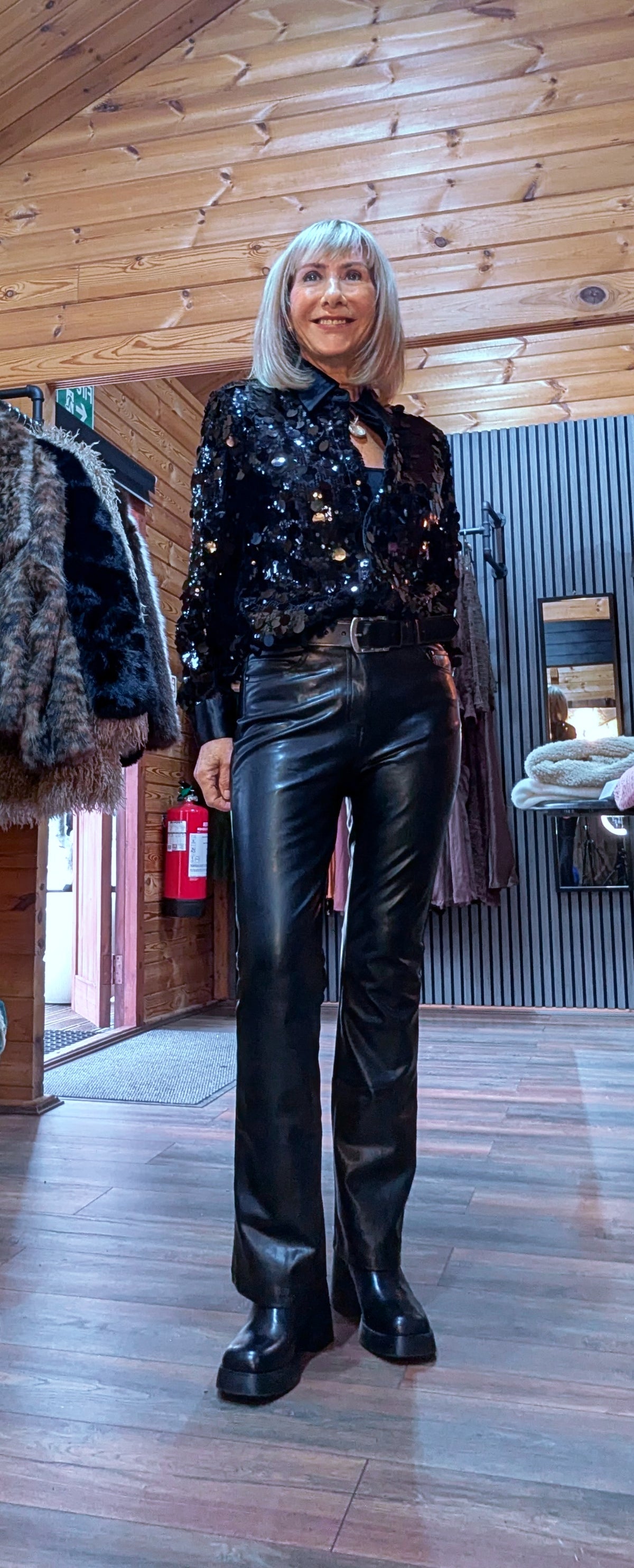 Shania black sequin blouse tucked into belted black trousers, styled with ankle boots.