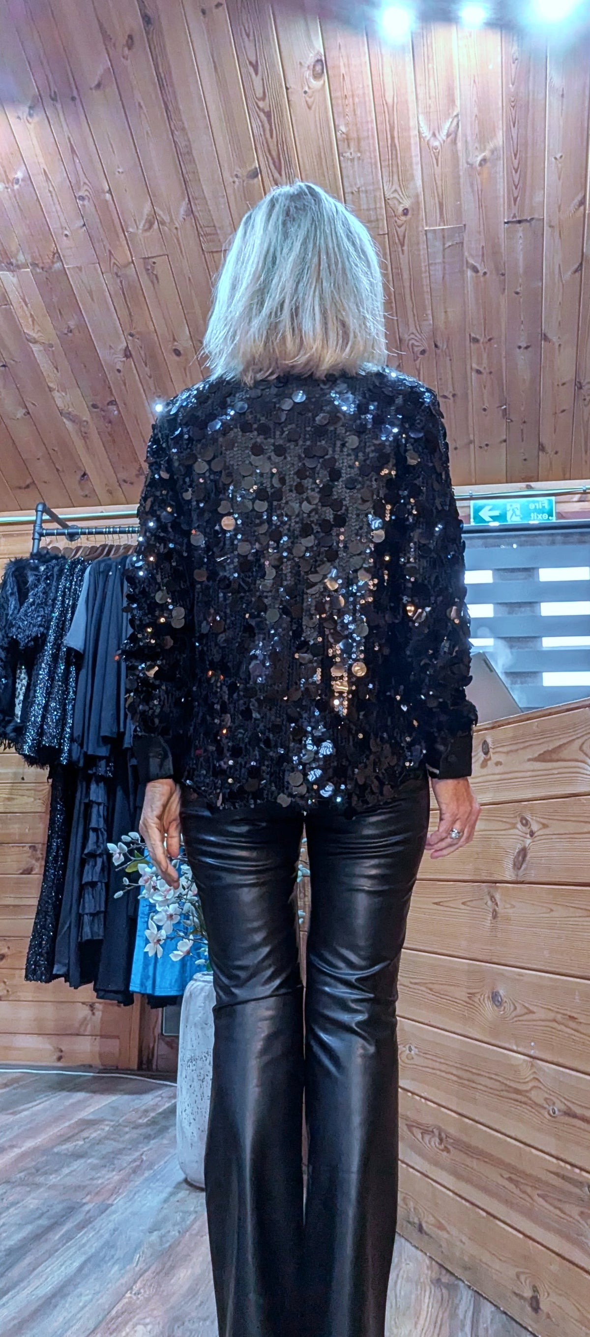 Back view of the Shania black sequin blouse, showing its long sleeves and hem.