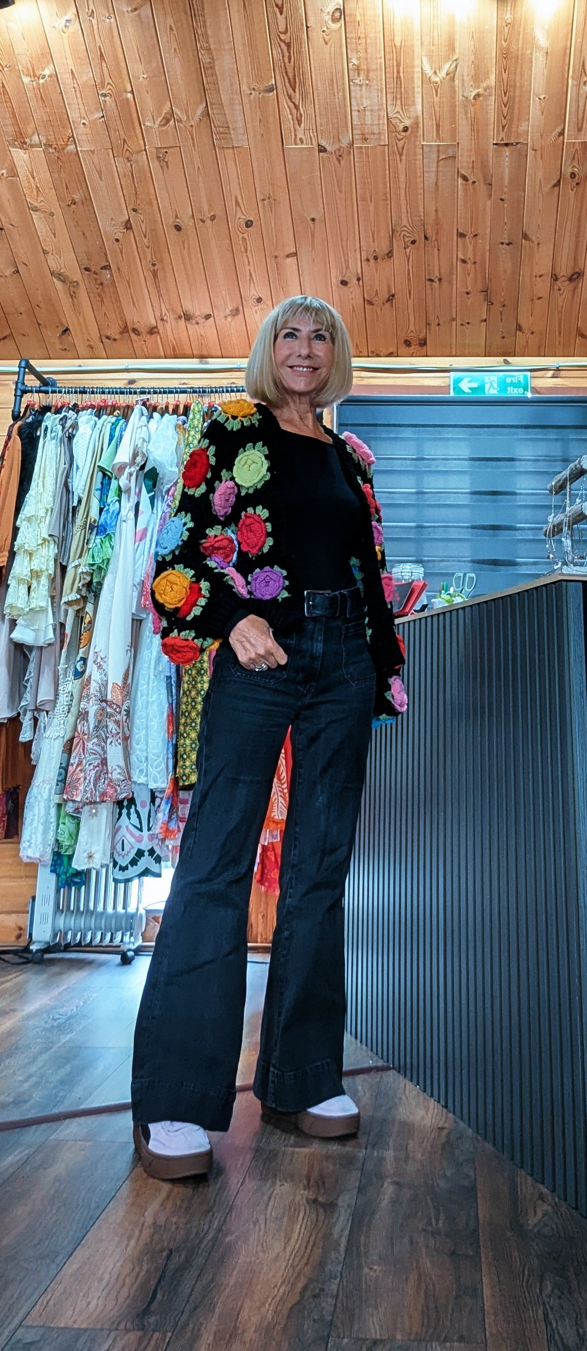 Woman wearing the Ora black crochet cardigan with statement 3D flowers
