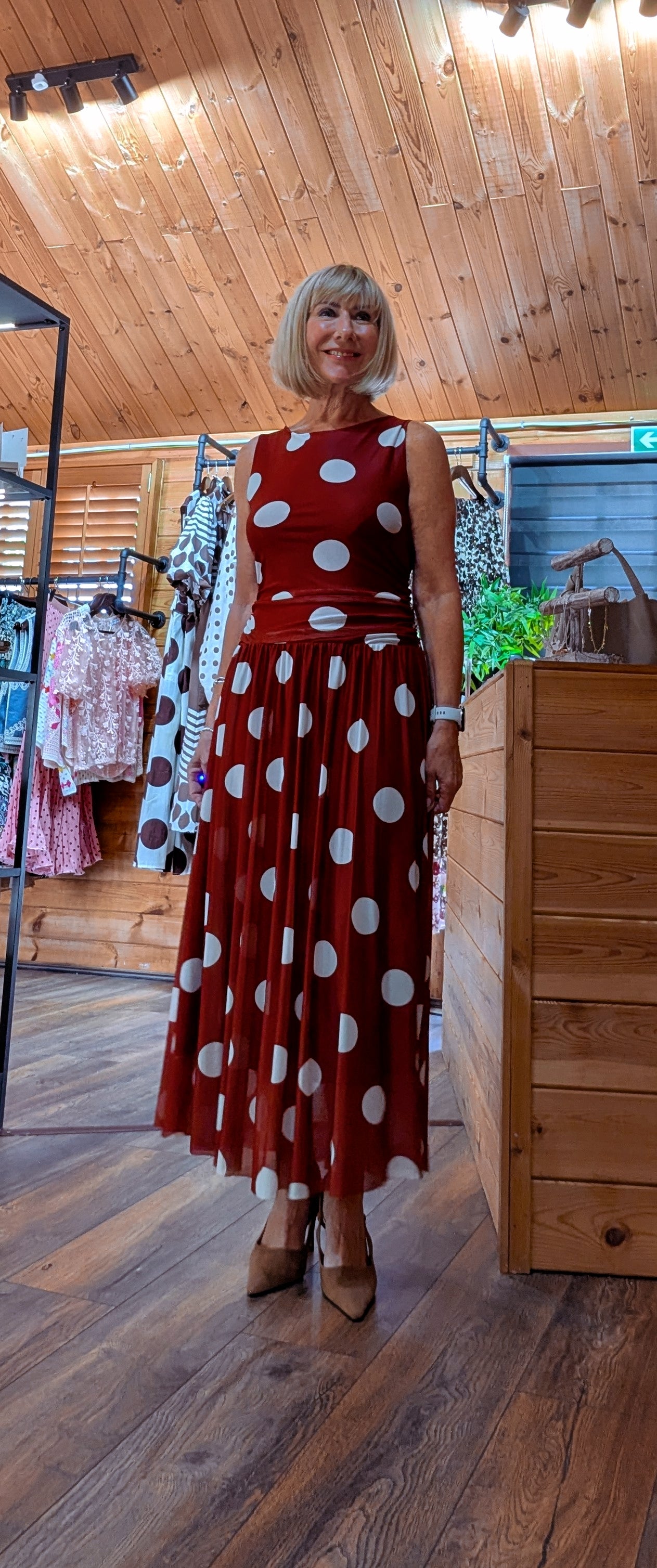 Woman wearing the Rumer rust-red maxi dress with oversized cream polka dots and a ruched waist