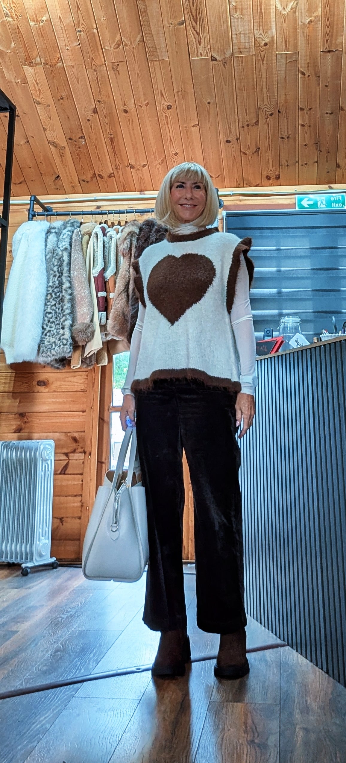 Maura heart sweater styled with a white shirt, dark trousers and a light-coloured handbag