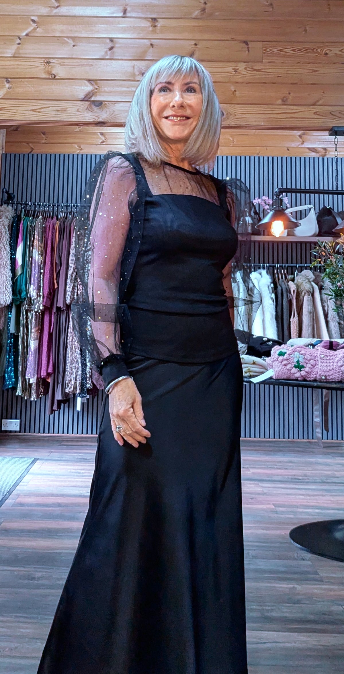 Three-quarter view of Sia black top with sheer sleeves gathered into black cuffs