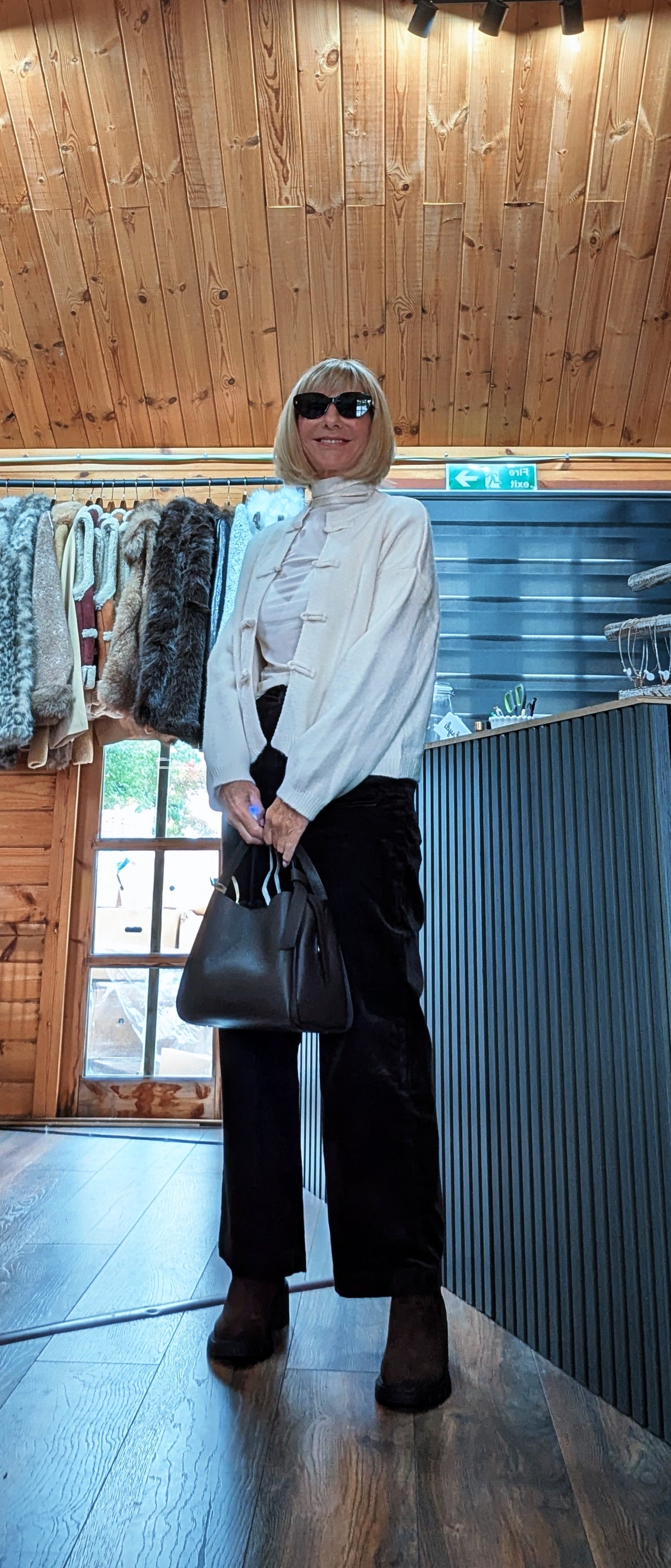 Fran cream knot-fastening cardigan worn with sunglasses, boots and a black handbag
