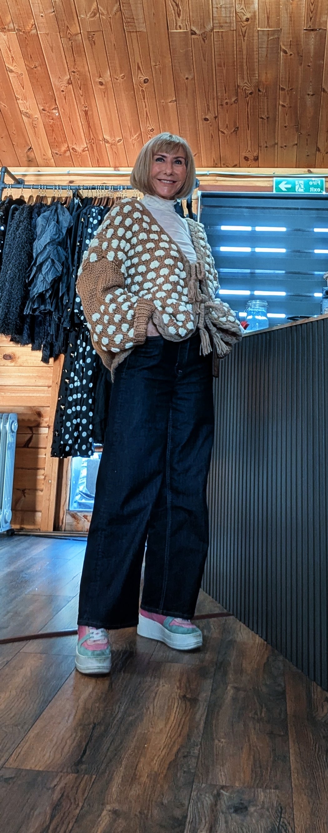 Three-quarter view of Abby beige cardigan with tassel ties, styled with dark jeans