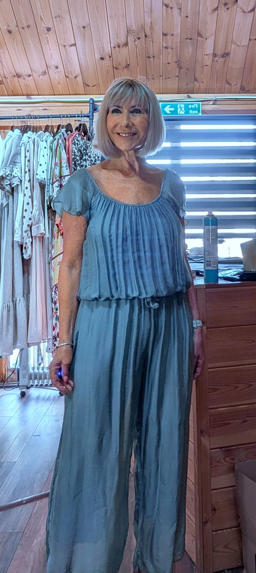 Jess aqua silk blend jumpsuit featuring an elasticated neckline that can be worn on or off the shoulder, with a flattering tie waist and wide-leg fit. One size fits UK 8–14.