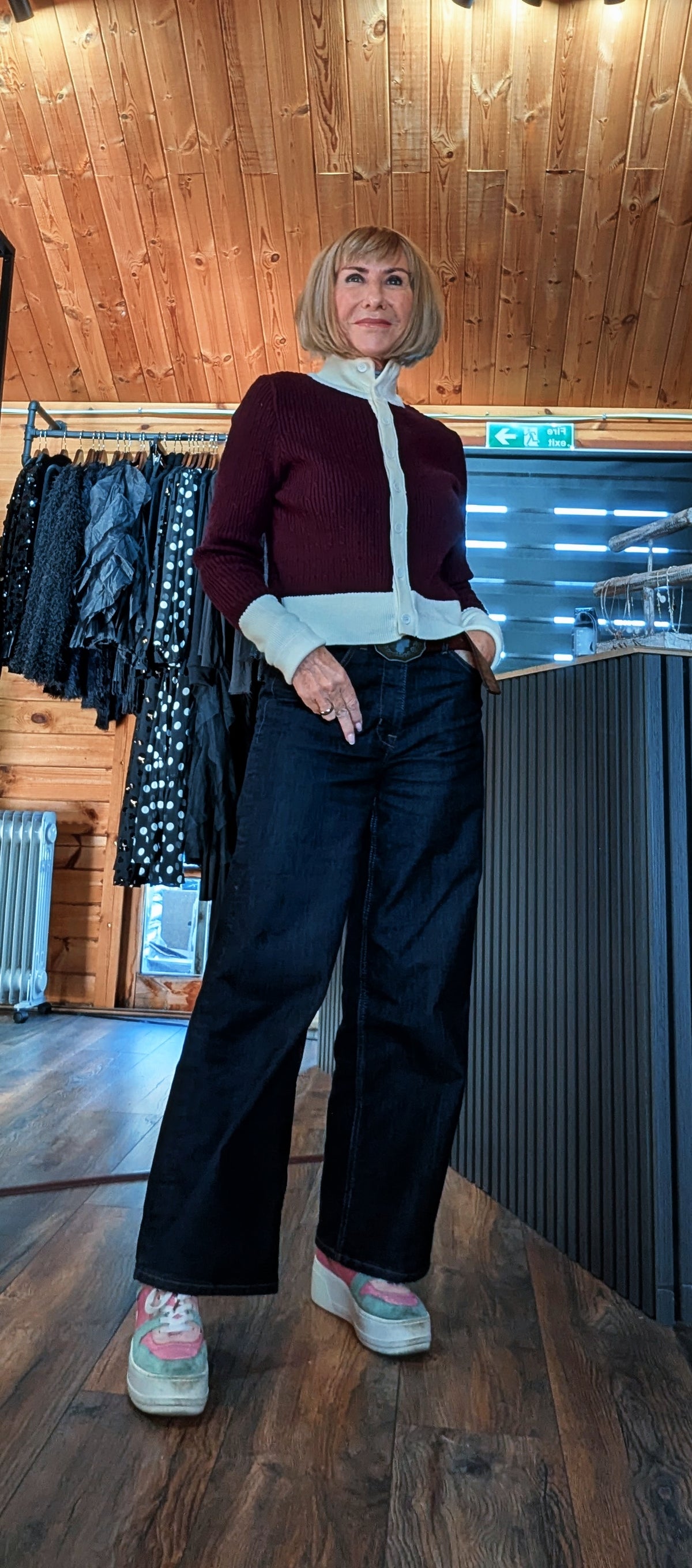 Full-length view of Mallory burgundy contrast-trim cardigan styled with jeans and pink trainers