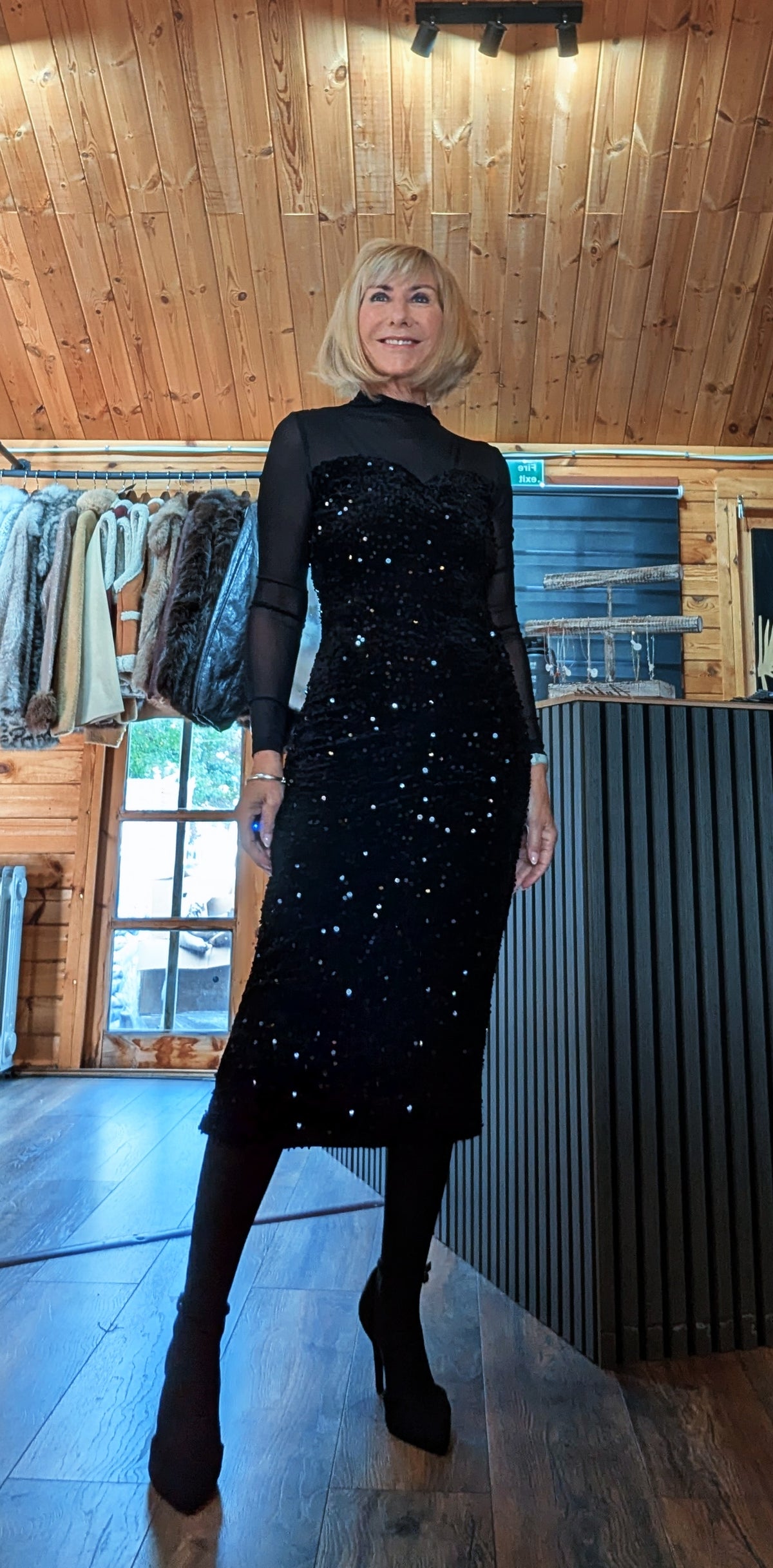 Di modelling Audrey with feet apart, showing the black sequin skirt and sheer sleeves.