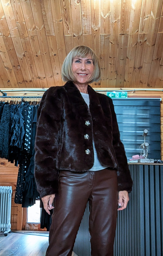 Front view of Bessie chocolate faux fur jacket showing its wide collar and flower-shaped jewel buttons.