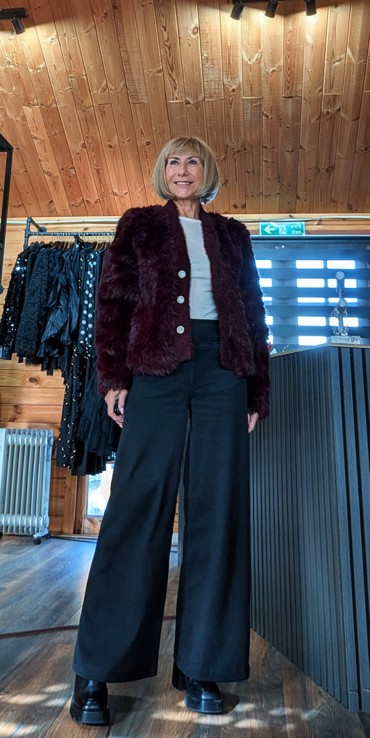 Full-length outfit with the Lumi burgundy faux fur jacket and black wide-leg trousers