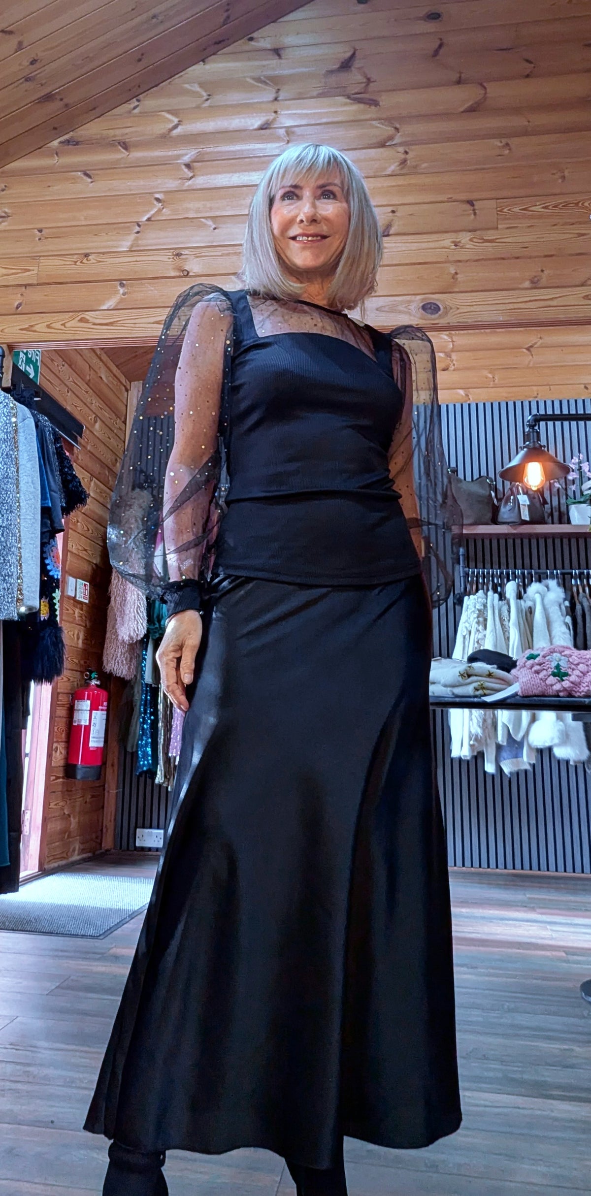 Angled outfit view of Sia sheer-sleeve black top paired with a flowing midi skirt