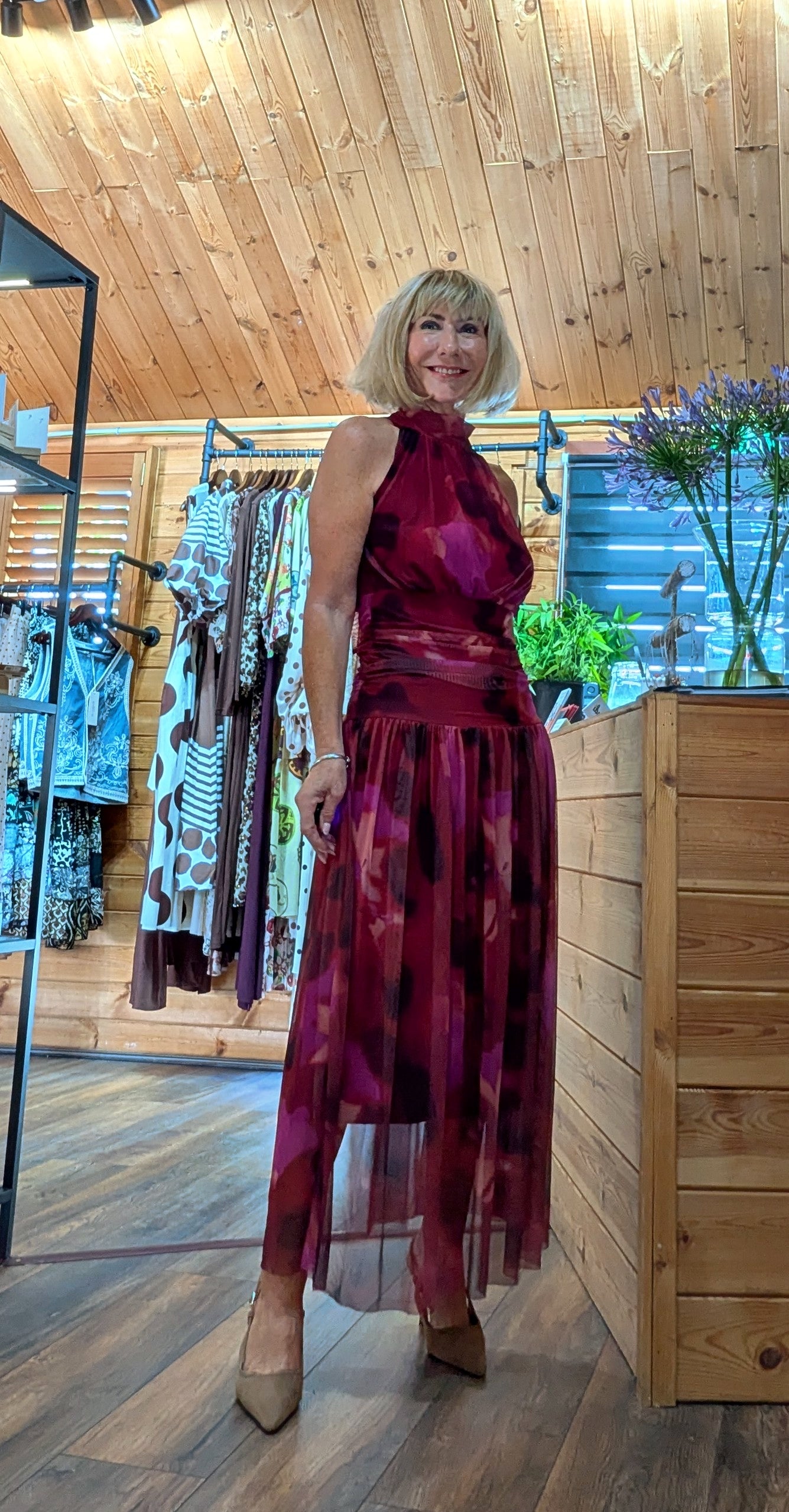 Model wearing a  sleeveless, high-neck, occasional halter dress in a vibrant magenta and deep red tie-dye pattern, fully lined tulle floaty skirt
