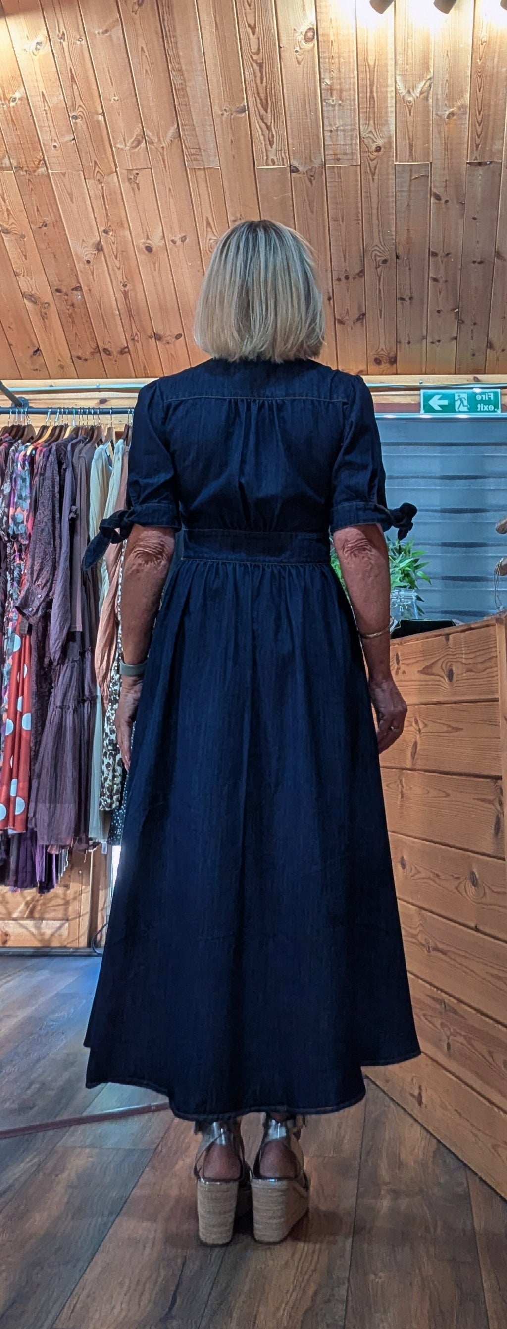Binty viewed from behind wearing  Binty dark navy blue midi dress with ruffled sleeves and a gathered waist