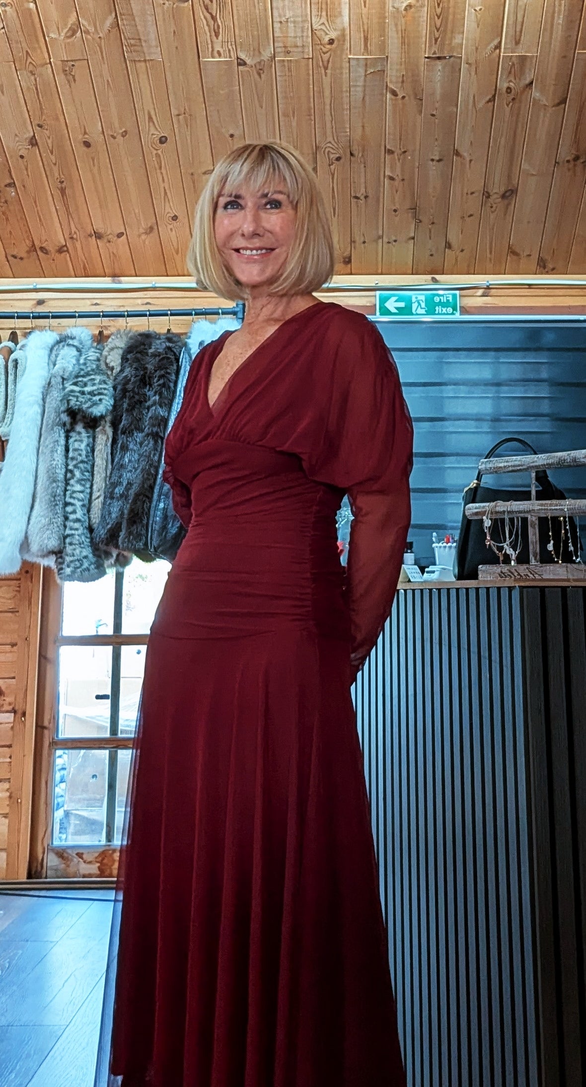 Three-quarter view of Luna burgundy dress showing the draped bodice and long sheer sleeves