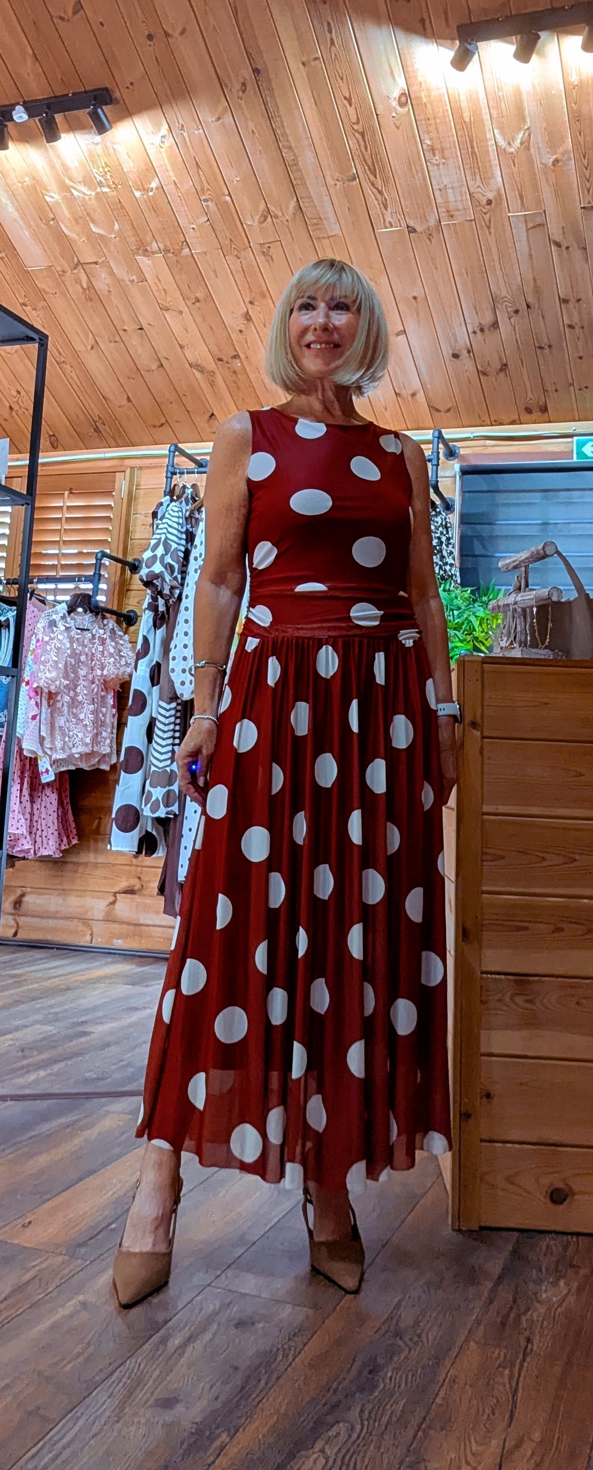 Woman wearing the Rumer rust-red maxi dress with oversized cream polka dots and a ruched  and tutu skirt