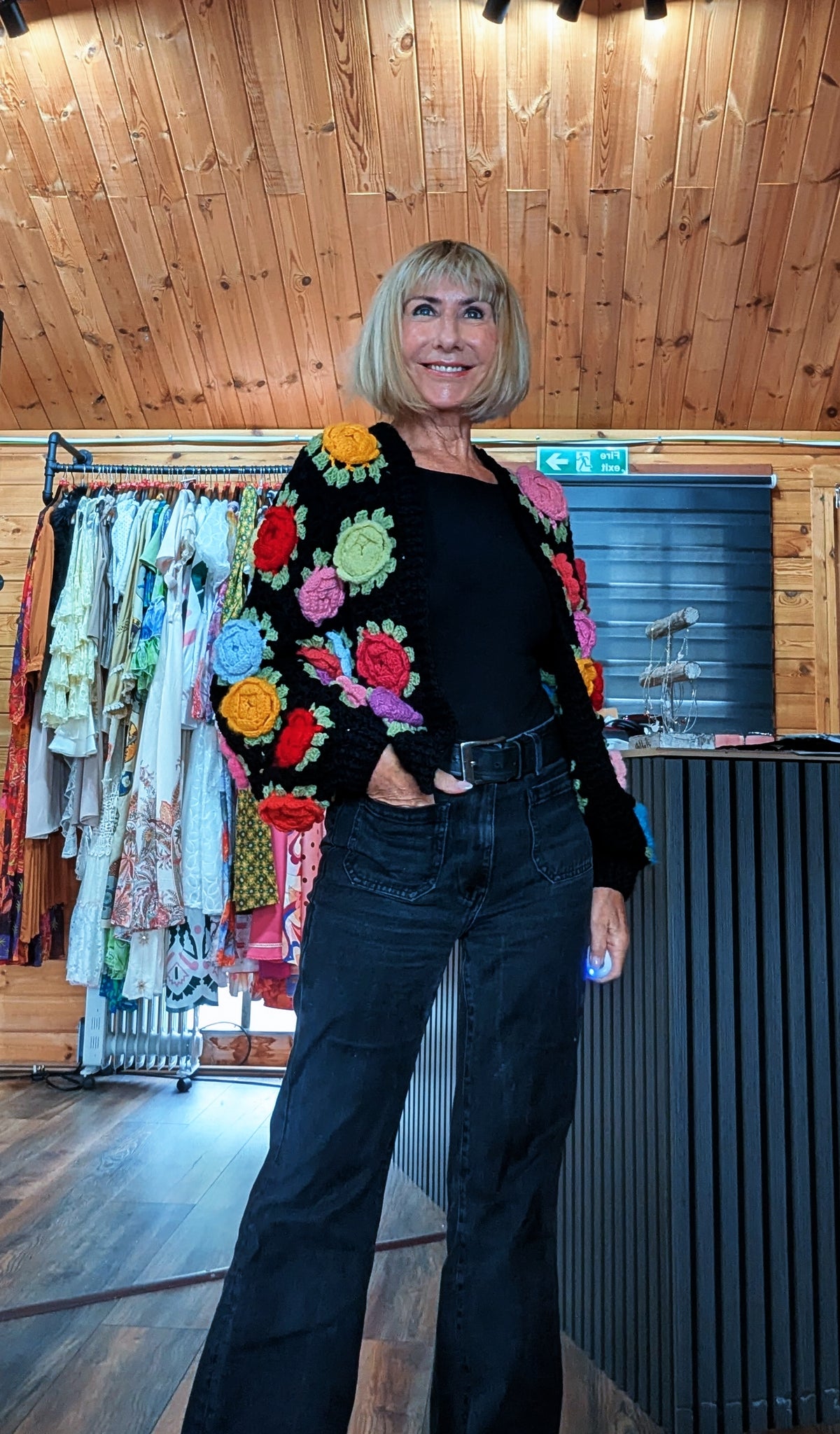 Black crochet cardigan with textured 3D flower appliqué detailing
