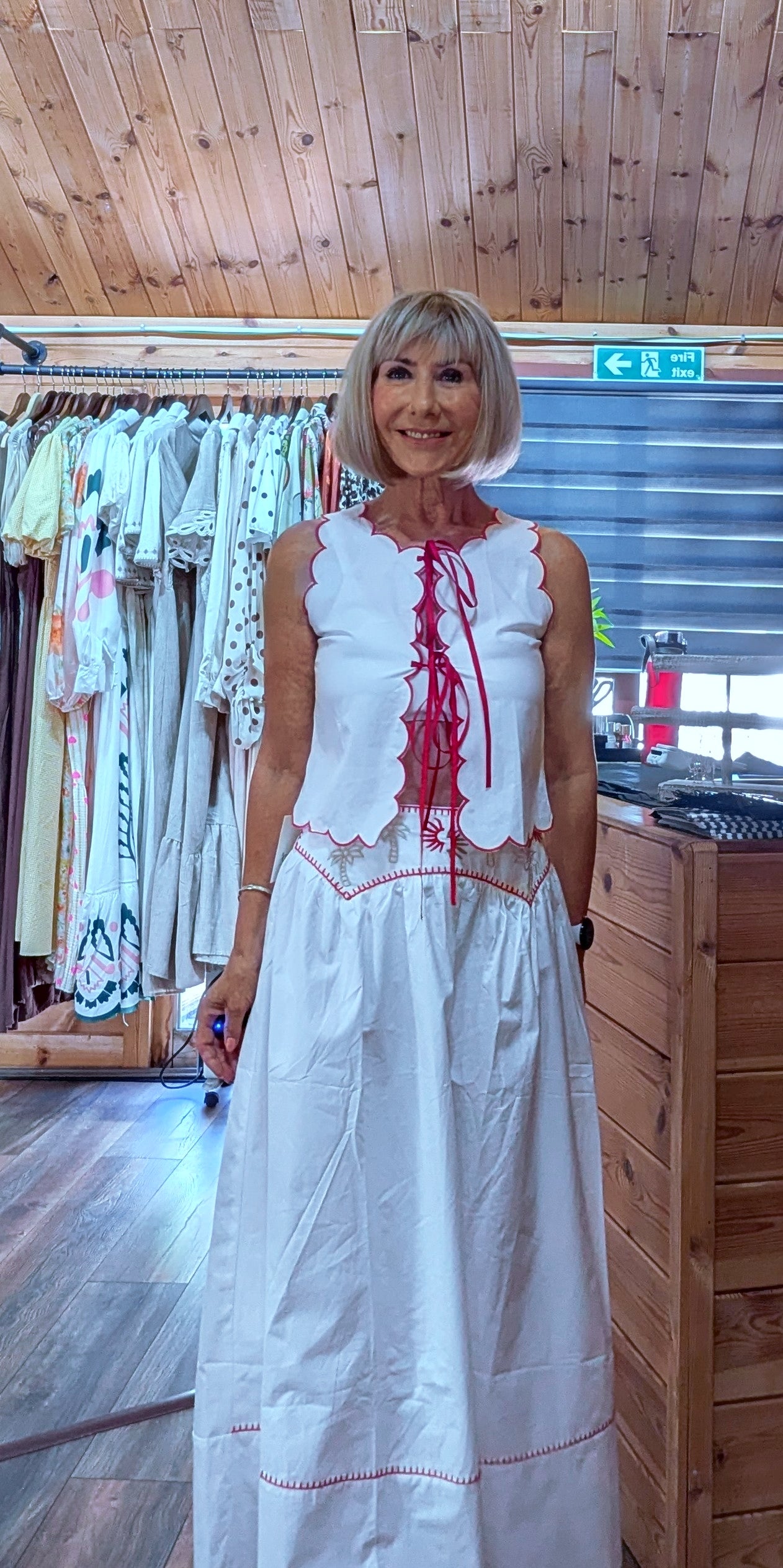 Model wearing the Iris white cotton top and skirt co-ord, a lightweight embroidered two-piece outfit perfect for holidays, garden parties and summer occasions.
