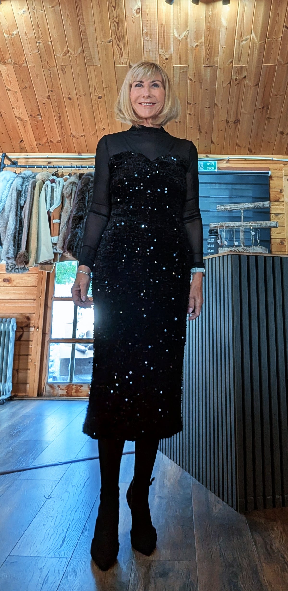 Audrey black sequin midi dress viewed from the front, showing its fitted shape and long sheer sleeves.