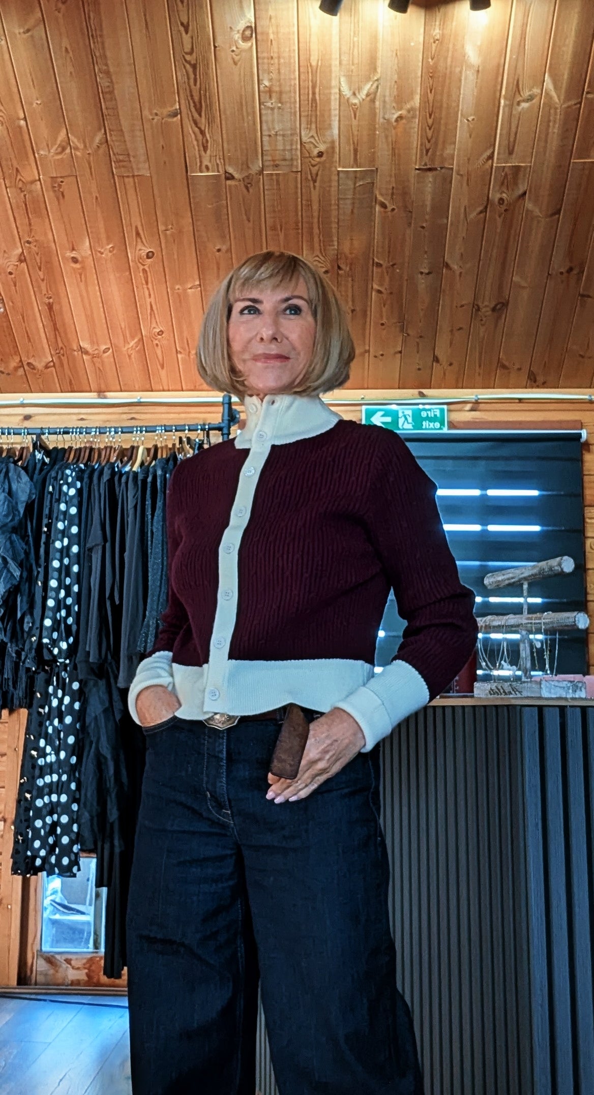 Mallory burgundy cardigan with cream collar, cuffs and button band, worn with dark wide-leg jeans