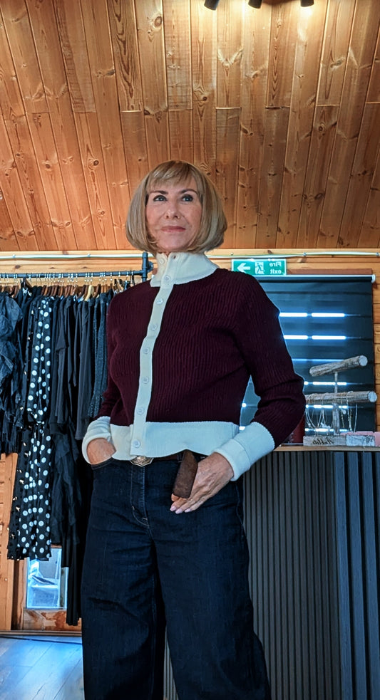 Mallory burgundy cardigan with cream collar, cuffs and button band, worn with dark wide-leg jeans