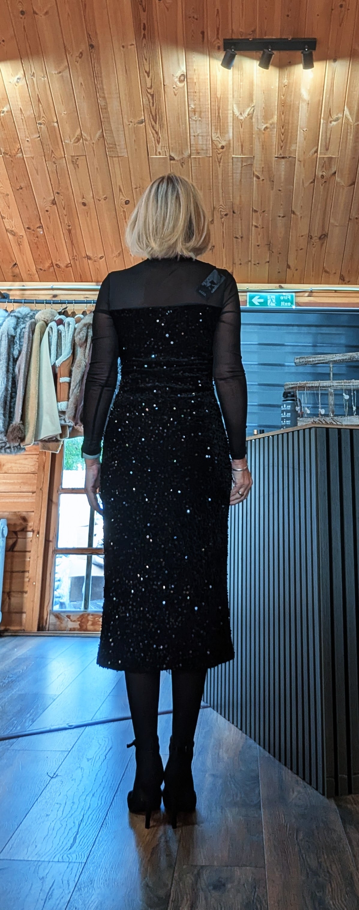 Back view of the Audrey black sequin dress showing the sheer upper back and sparkling skirt.