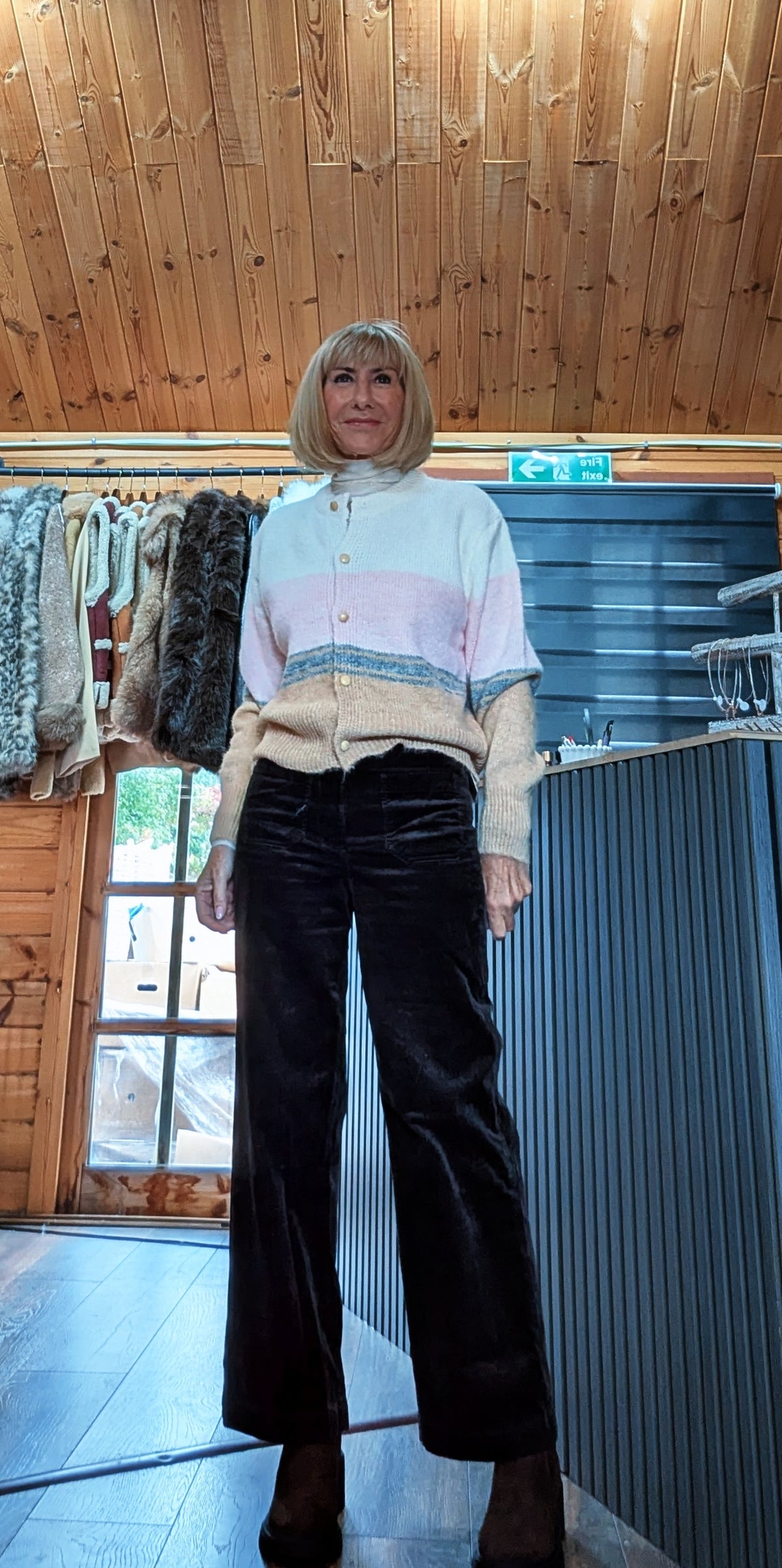Full-length view of Helen colour block cardigan worn with dark wide-leg trousers and boots