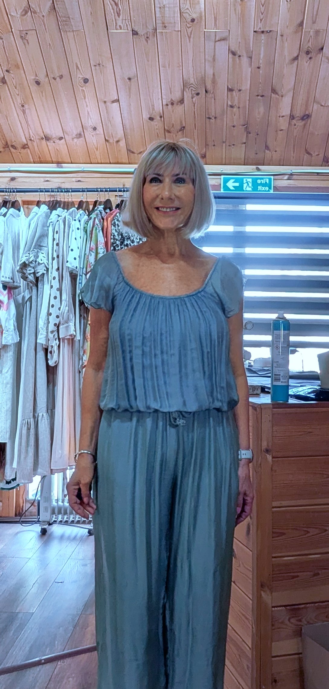 Lightweight aqua silk blend jumpsuit designed with an elasticated neckline, tie waist and flowing wide legs, suitable for UK sizes 8–14.