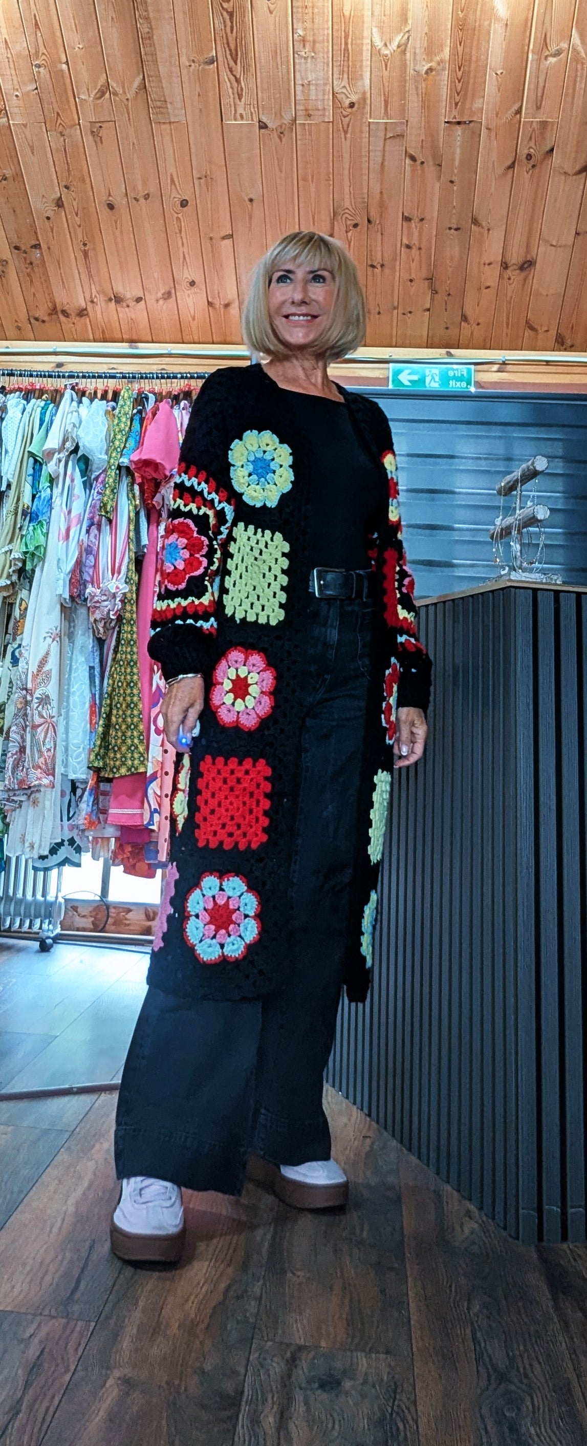 Black open-front long cardigan featuring colourful red, green, yellow and blue crochet flowers

