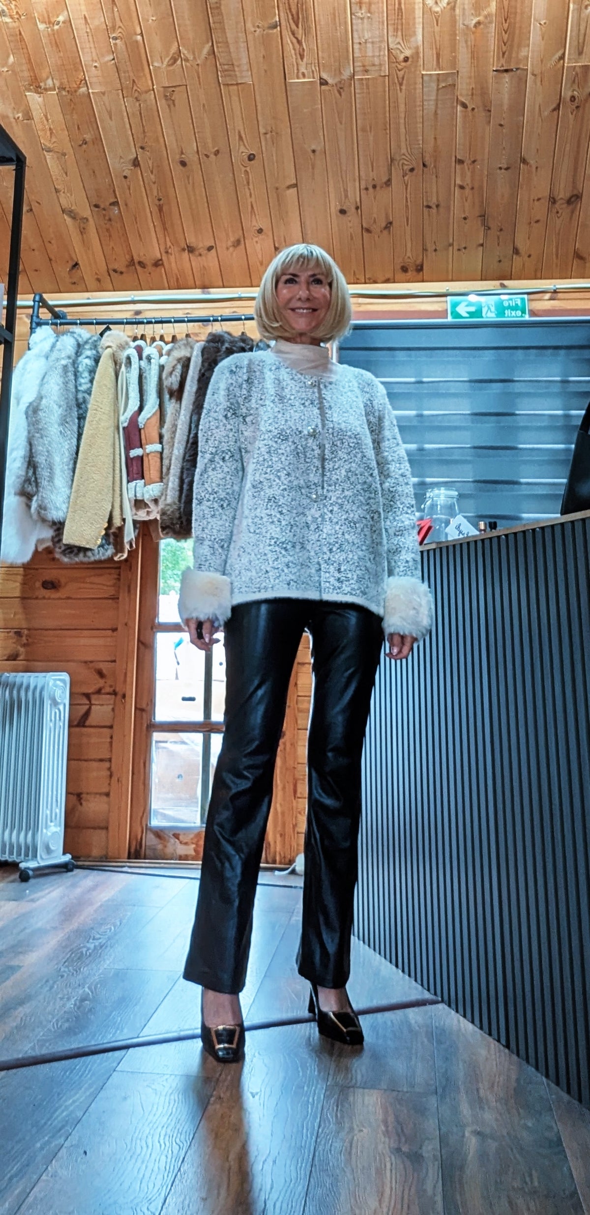 Full-length view of Liv white knit cardigan worn fastened with black trousers and heels