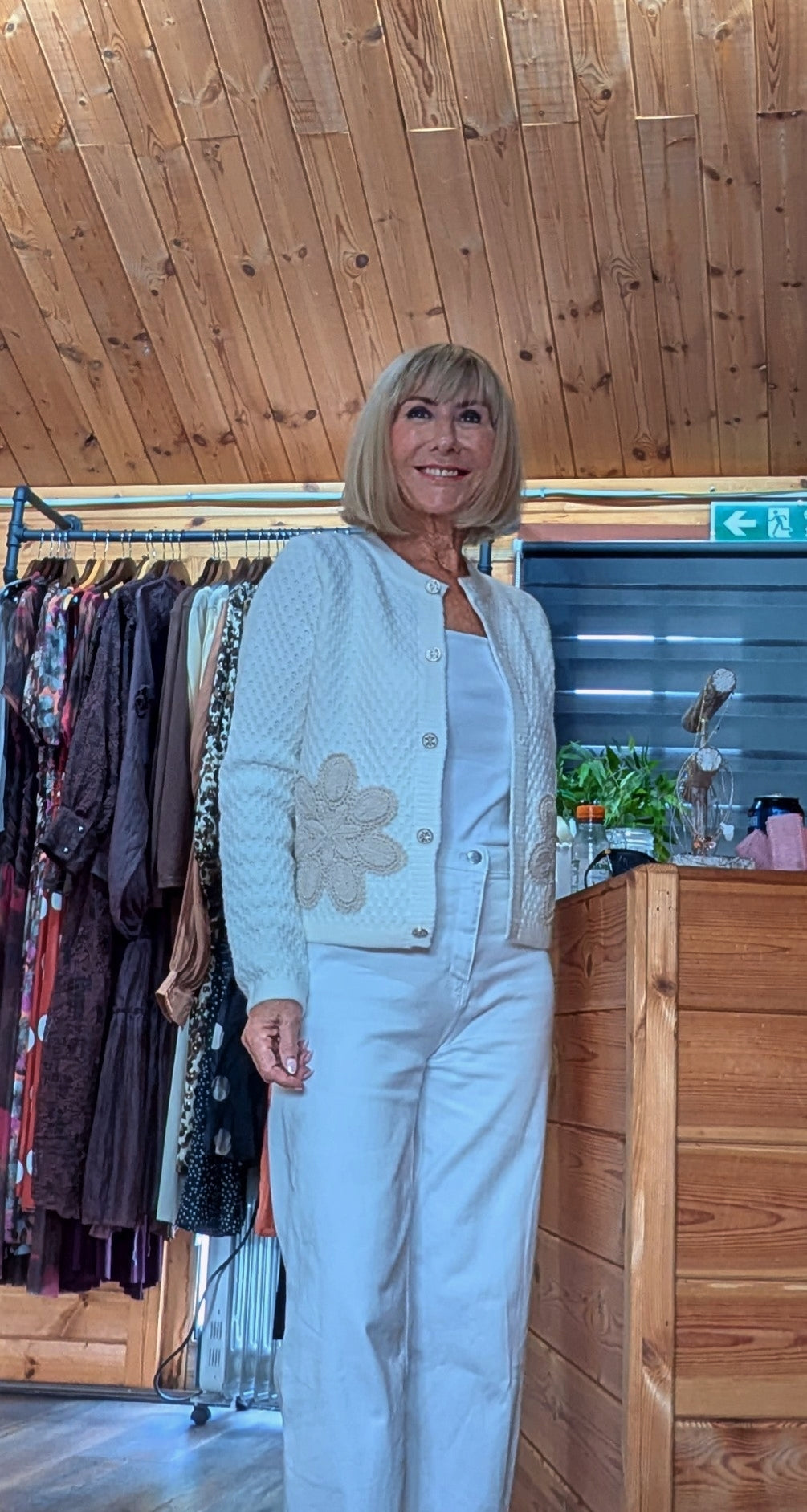 Ivory button front cardigan with decorative flower detail and textured knit.